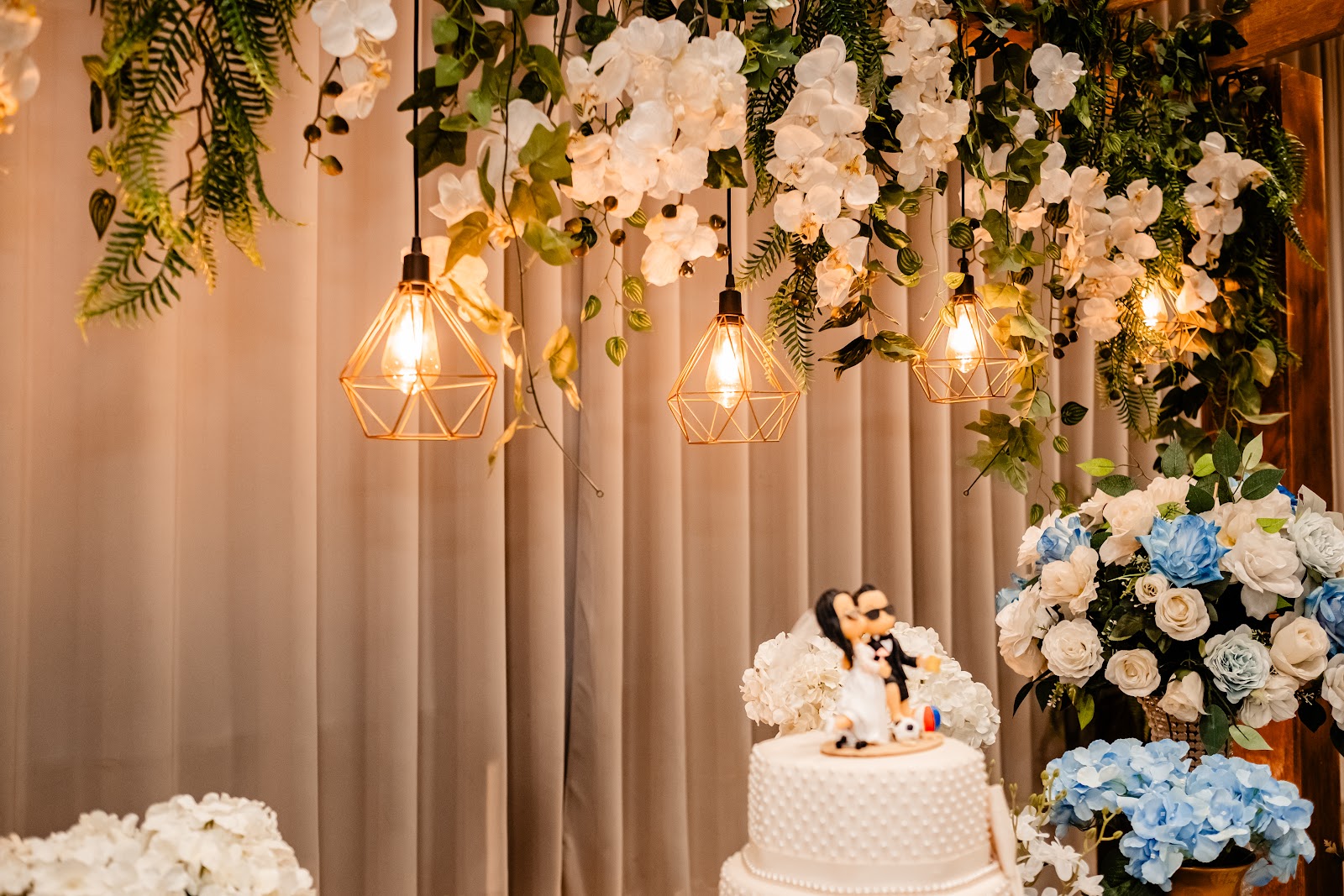 Salão com mesas decoradas e cortinas iluminadas